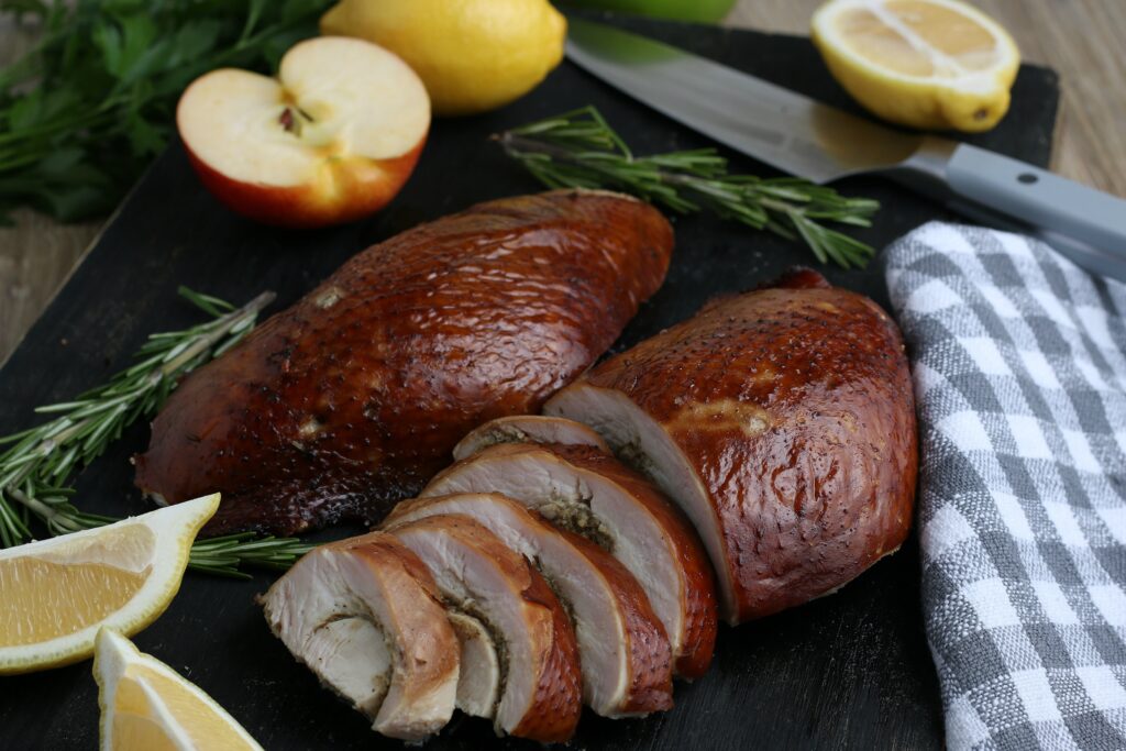sliced smoked turkey on black cutting board, served with lemons and apples