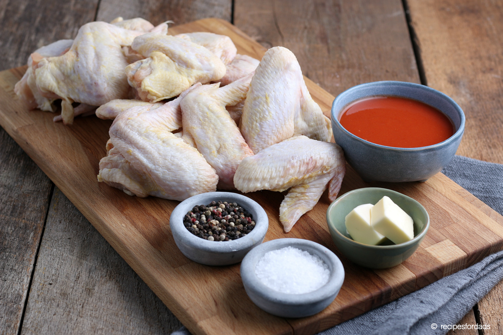 raw chicken wings and seasoning displayed on brown cutting board