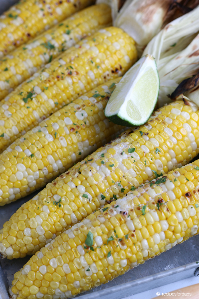 Corn on the cob seasoned with butter and parmesan cheese, served in a silver tray