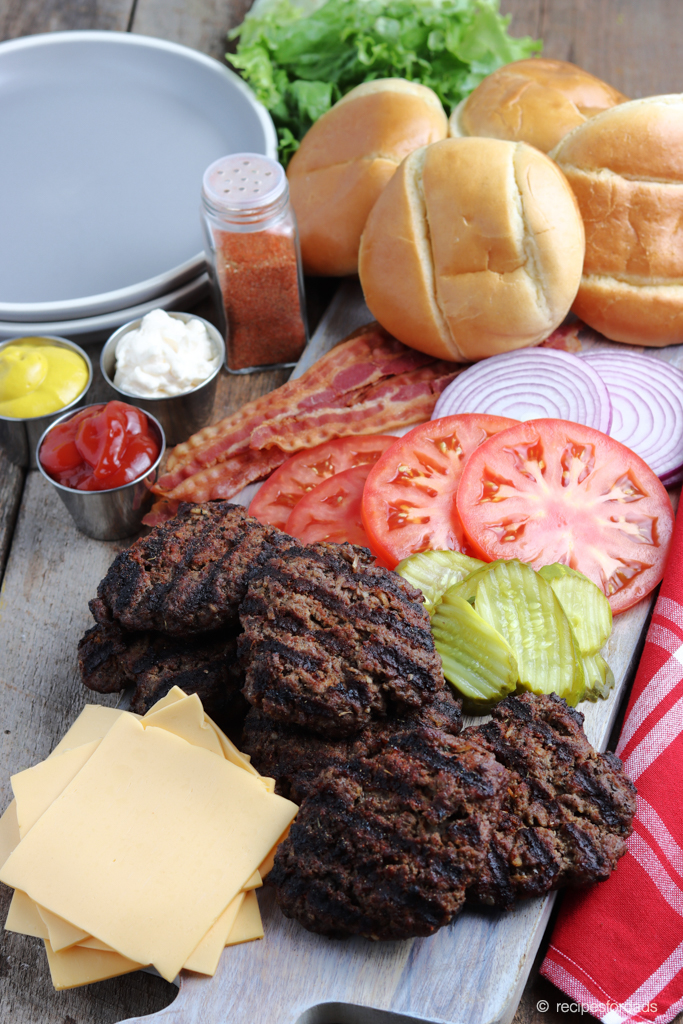 Juicy Grilled Burgers served with tomatoes, pickles, lettuce and buns