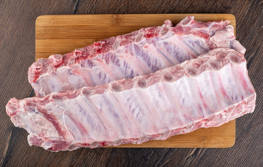 Top view of strips of raw pork ribs. Fresh meat on a cutting board.