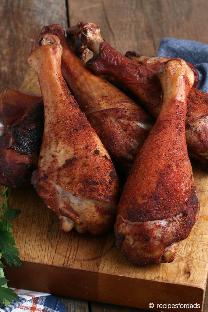 smoked turkey legs served on a cutting board with blue and red napkin