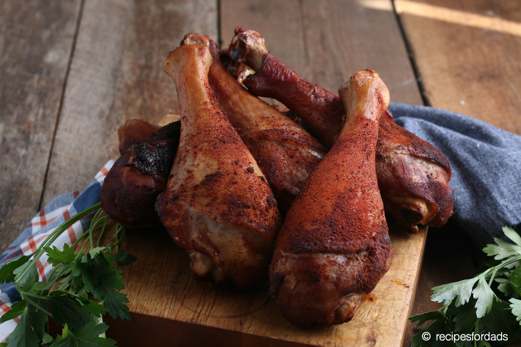 smoked turkey legs served on a cutting board with blue and red napkin