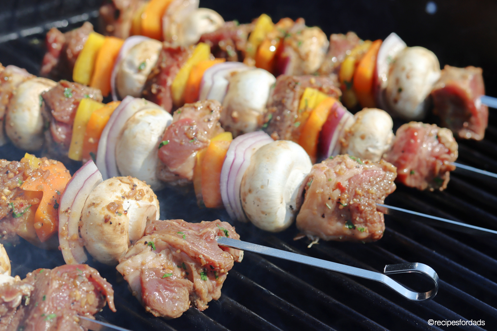 beef kabobs with metal skewers cooking on the grill