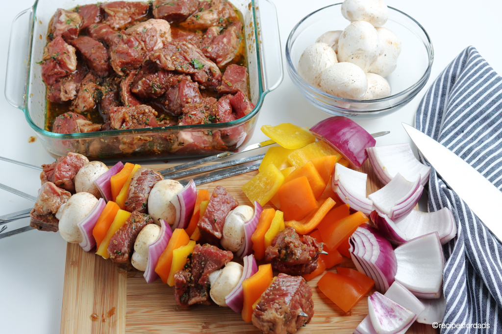 beef kabobs marinating with vegetables chopped on serving board