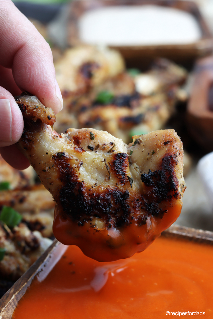 dipping chicken wing in hot sauce