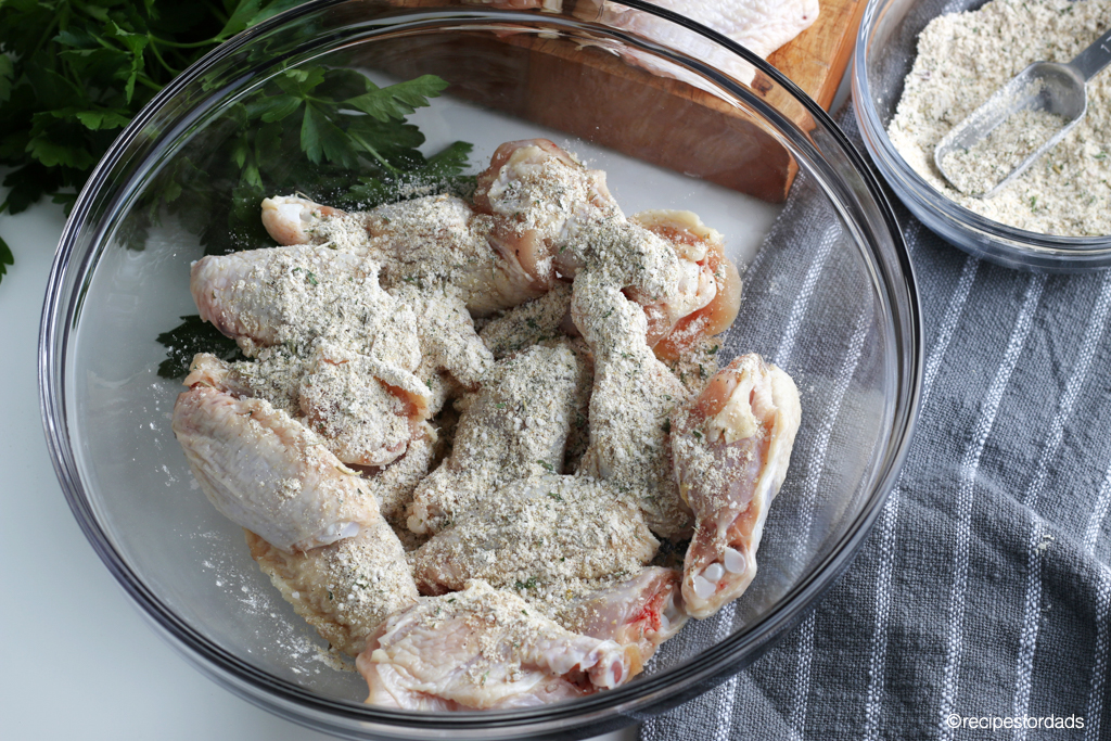 dry rub on raw chicken wings in glass bowl