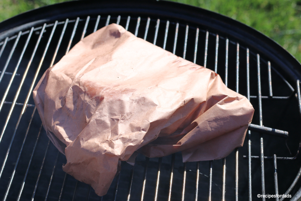 brisket wrapped in butcher paper, smoking on a weber smokey mountain smoker