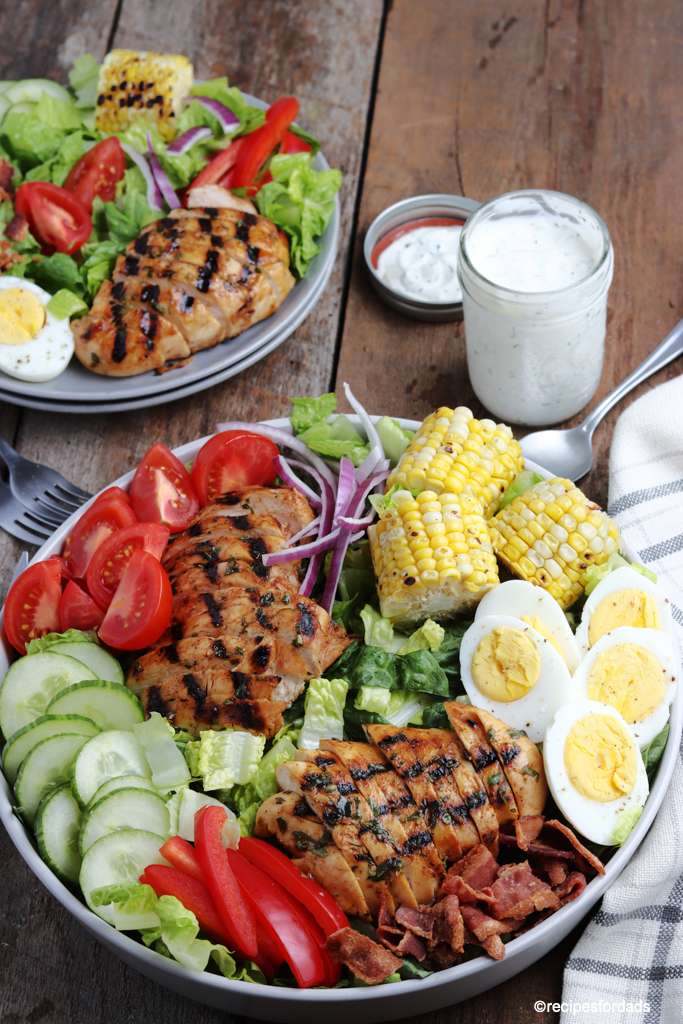 delicious grilled chicken cobb salad served with corn on the cob and boiled eggs, paired with ranch dressing