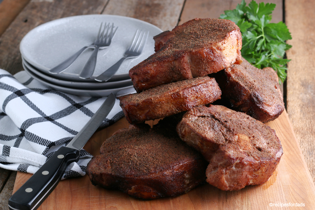 Six smoked pork chops displayed on cutting board with black and white napkin