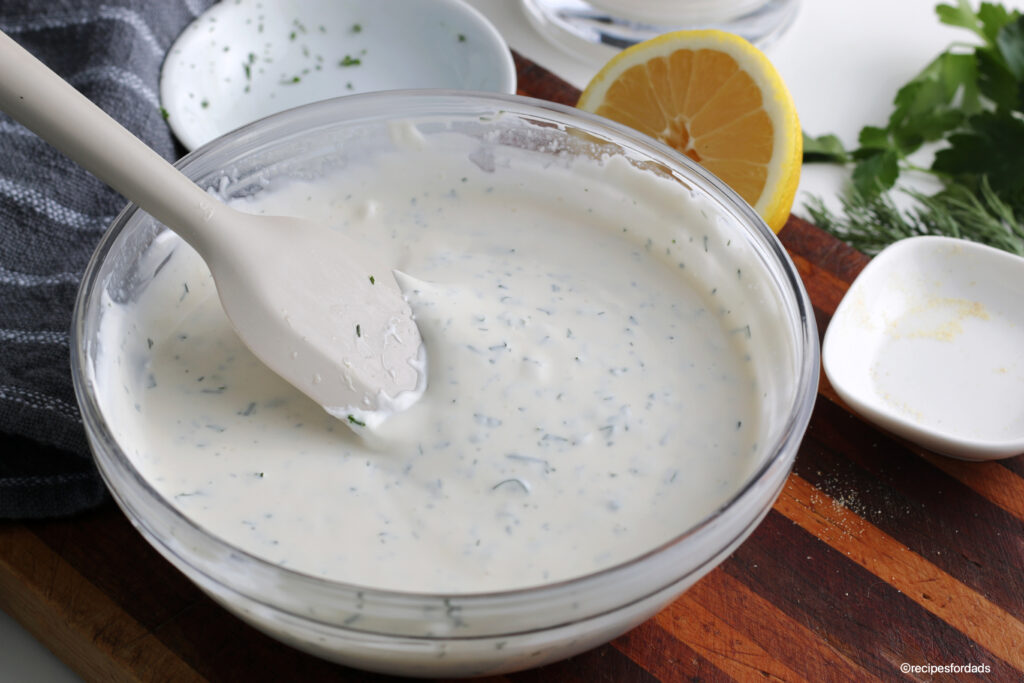mixing ingredients together to make homemade ranch dressing, displayed on wood board 