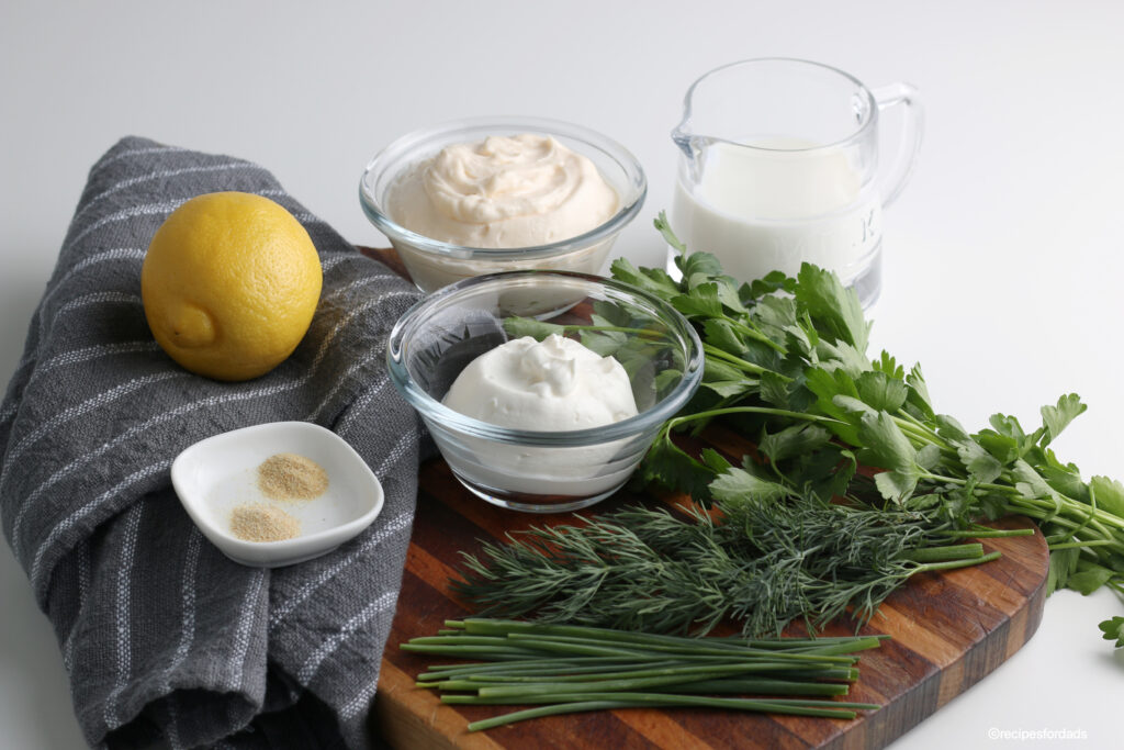 ingredients to make homemade ranch dressing, displayed on wood board 