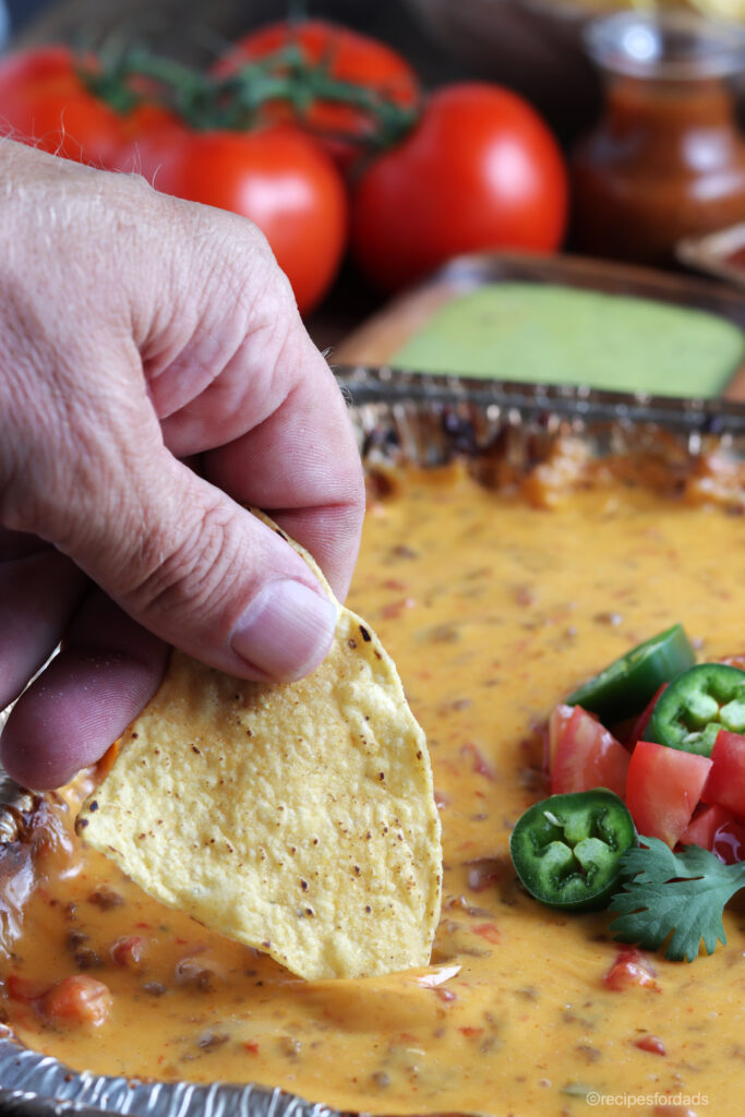tortilla chip dipping into the smoked queso dip