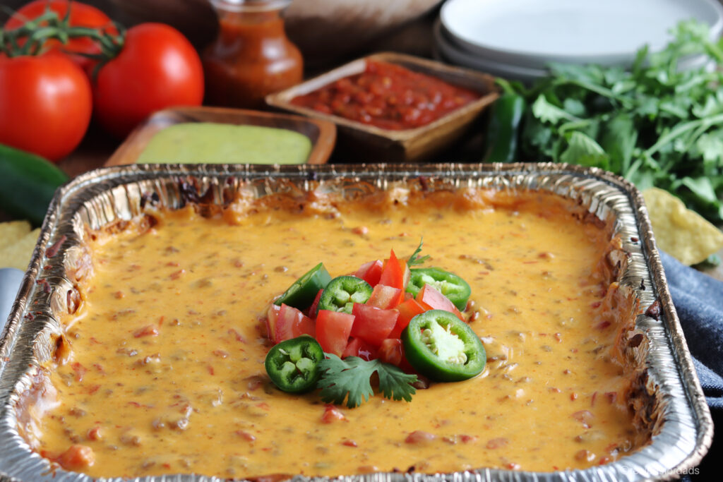 smoked queso dip topped with jalapeños and tomatoes