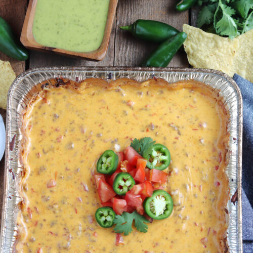 smoked queso dip topped with jalapeños and tomatoes
