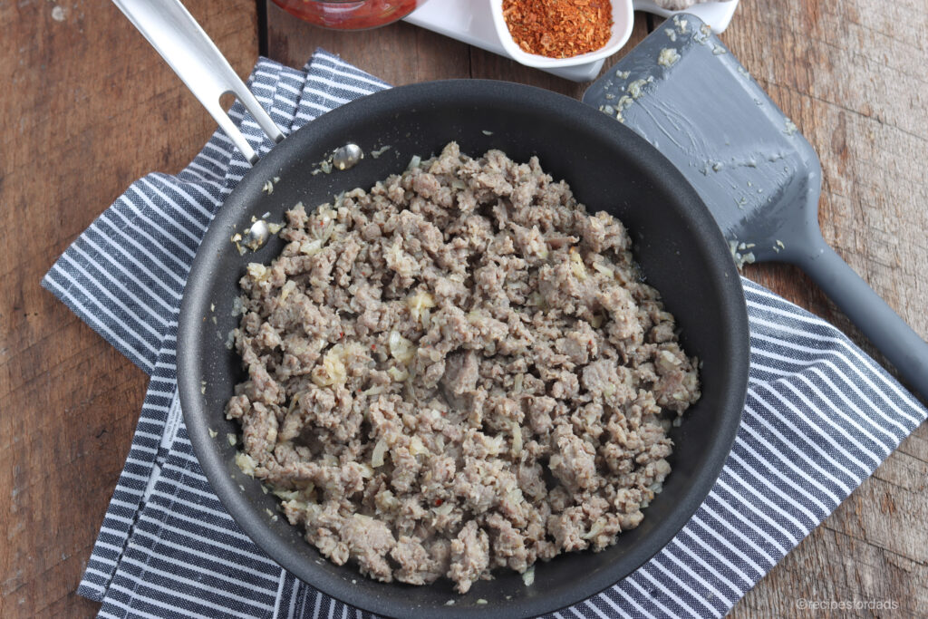 hamburger meat in a frying pan, mixed with onions
