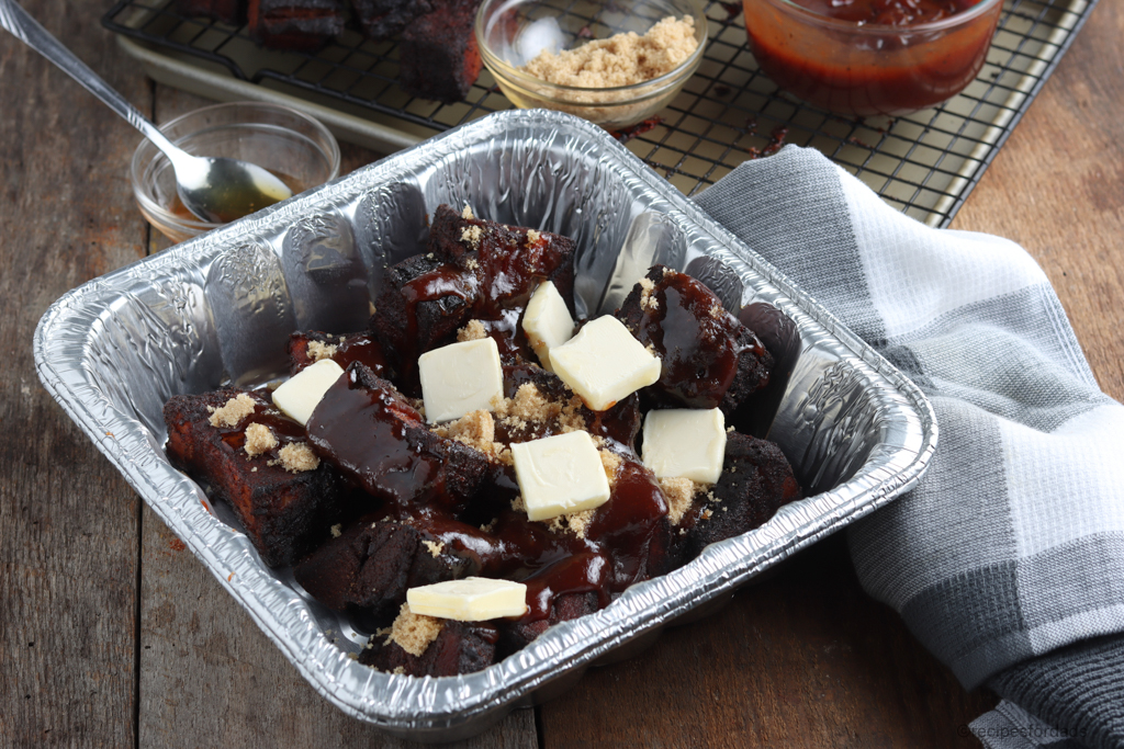 Butter and brown sugar smothering the burnt ends, in an aluminum pan