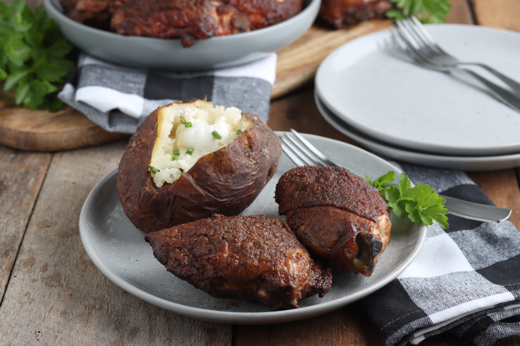 smoked chicken thighs served with smoked baked potato