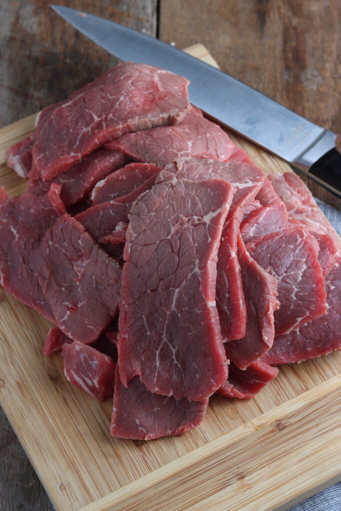 beef cut in thin slices on a cutting board