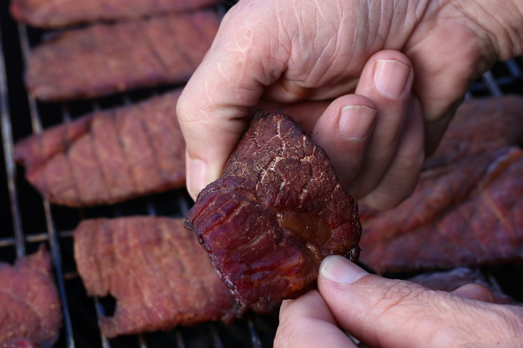 holding slice of Smoked Beef jerky