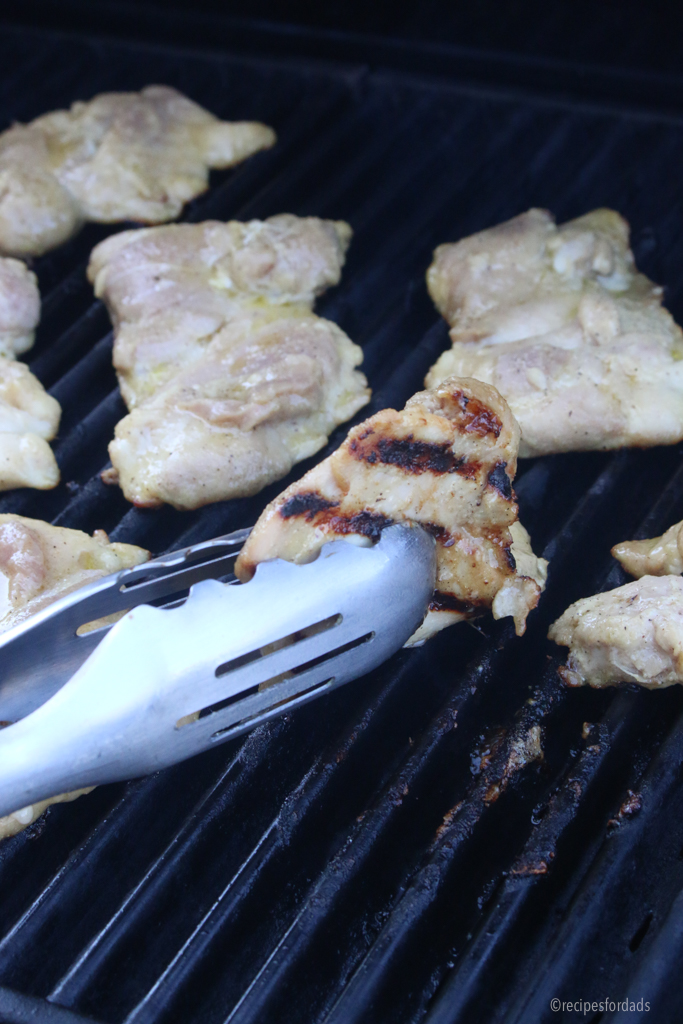 Turning grilled chicken.