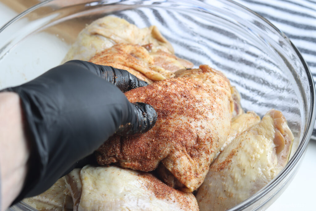 Seasoning chicken thighs with rub.