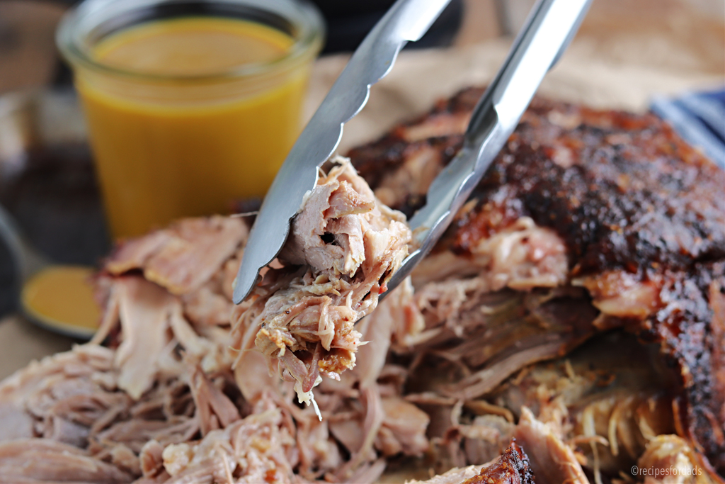 holding shredded pork shoulder with tongs