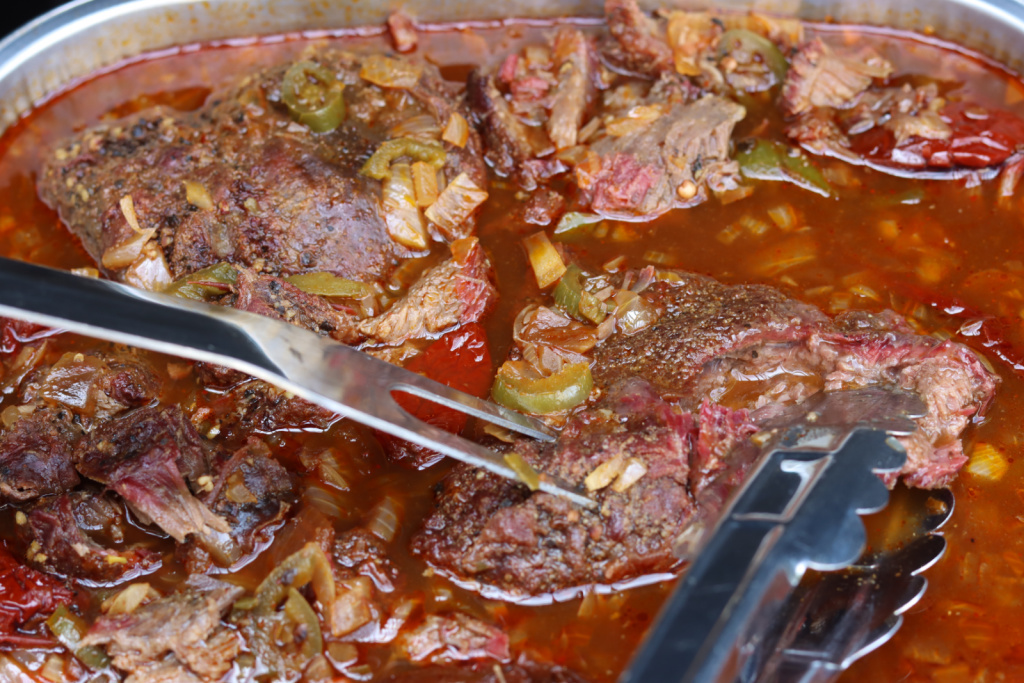 smoked barbacoa in sauce in foil pan with forks
