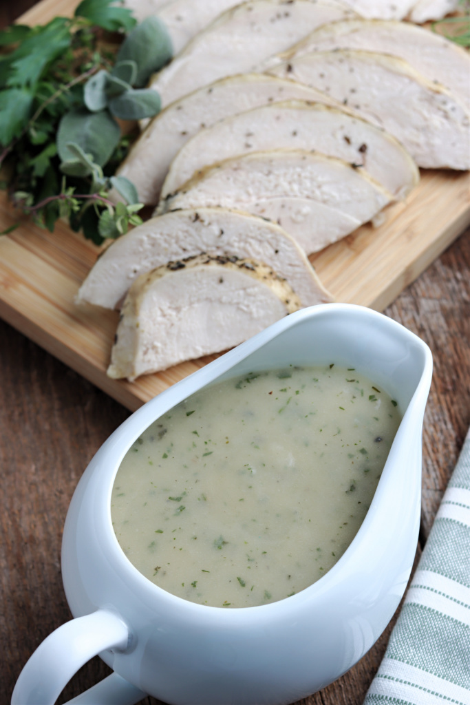 turkey gravy in white gravy boat and turkey on cutting board