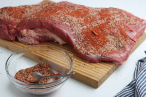 spices on beef brisket on cutting board