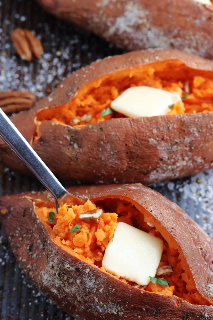 fork in a smoked sweet potatoes with butter, pecans and fresh parsley