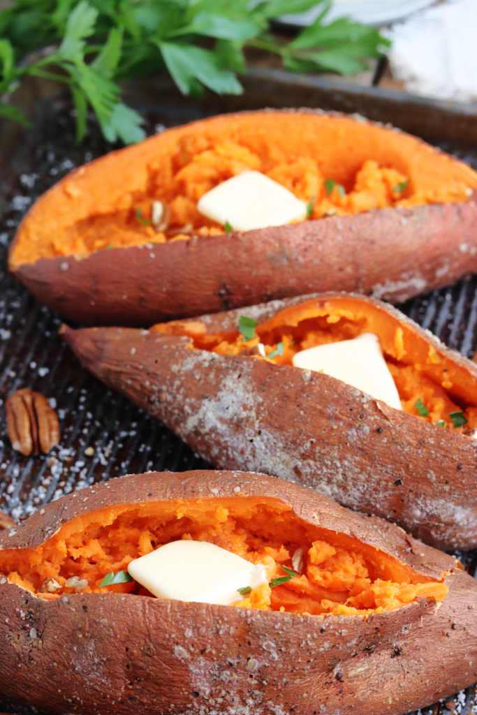 smoked sweet potatoes on a pan with butter, fresh parsley and pecans