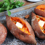 smoked sweet potatoes with butter, parsley and pecans on a pan