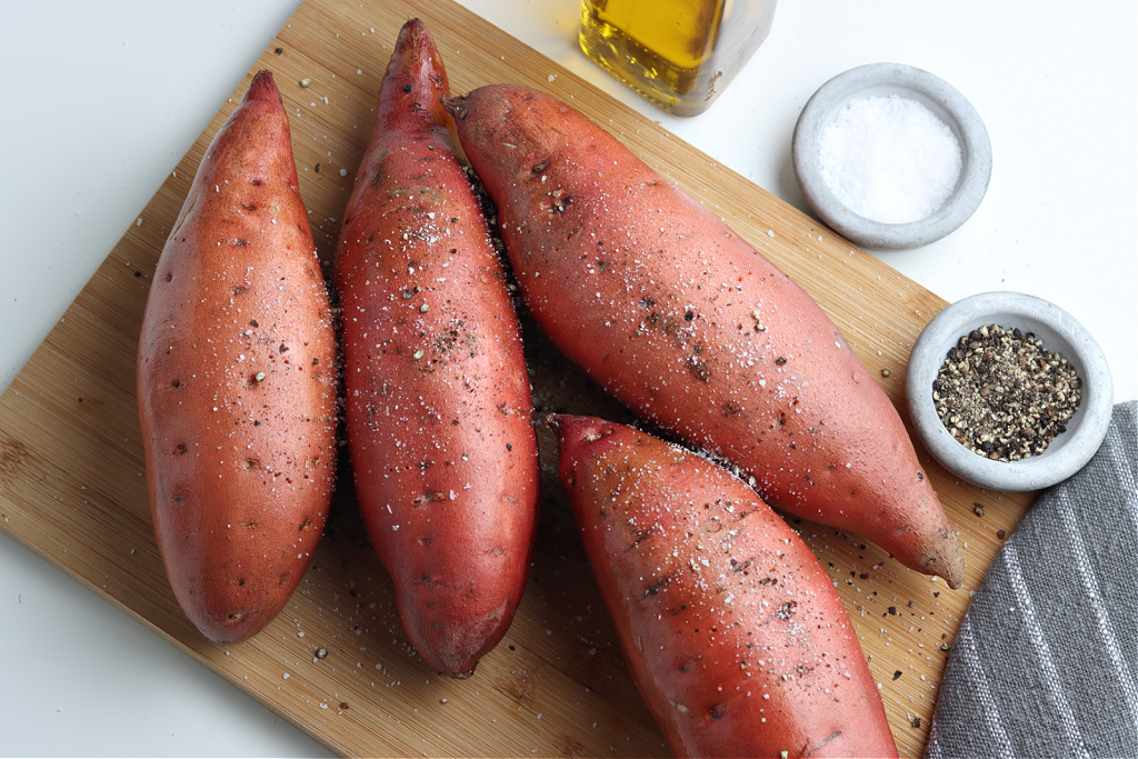 sweet potatoes on board with oil, salt and pepper