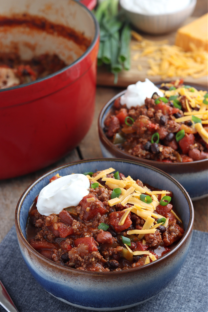 two bowls of smoked chili with cheese, green onions and sour cream